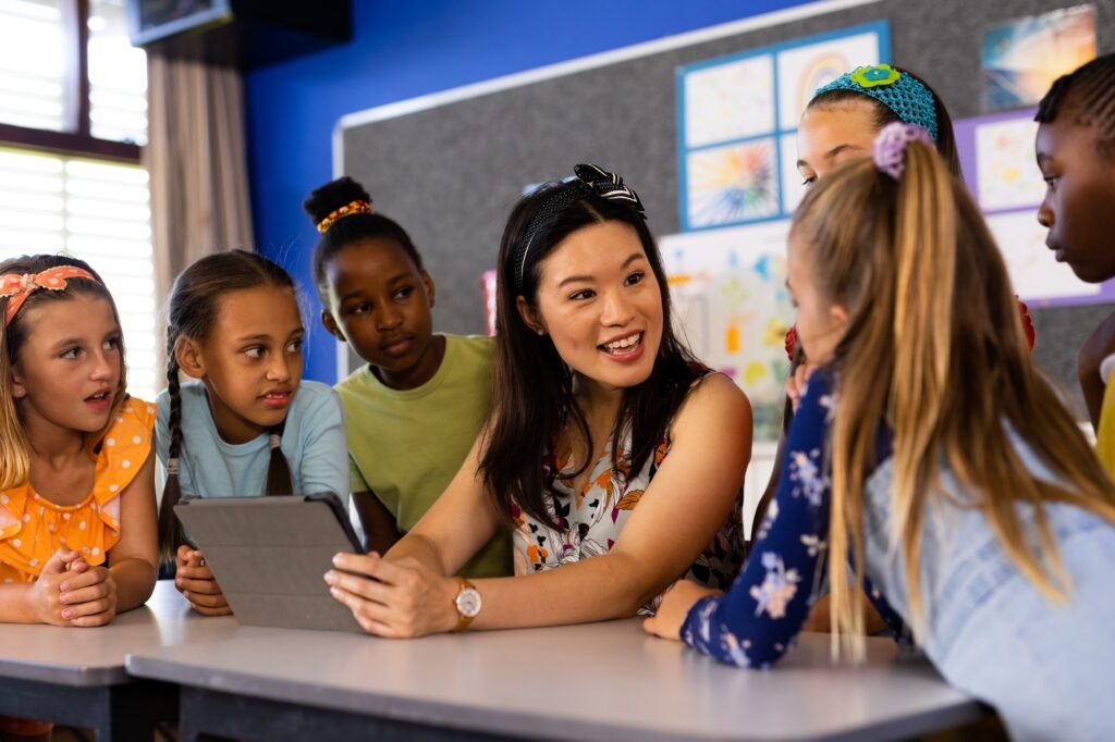 Diverse female teacher with tablet and elementary schoolgirls in class