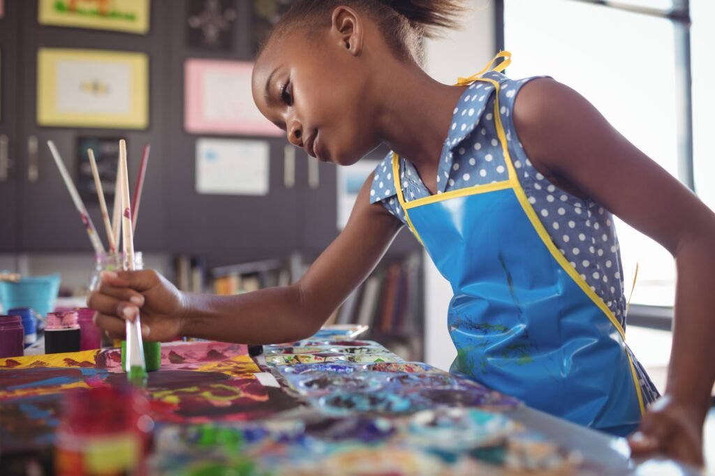 Focused elementary girl painting at desk